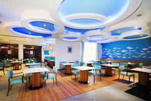 un restaurant avec des tables et des chaises et un plafond bleu dans l'établissement Grand Dafam Ancol Jakarta, à Jakarta