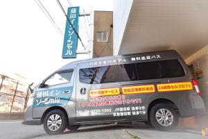 Una furgoneta con escritura aparcada al lado de un edificio en Kamata Inn Social, en Tokio