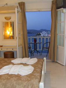 a bedroom with a bed with a view of the ocean at Pandrossos Hotel - Paros in Parikia