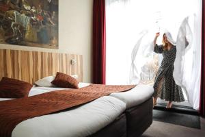 Una mujer está mirando por la ventana de una habitación de hotel en Hotel Asterisk, a family run hotel, en Ámsterdam