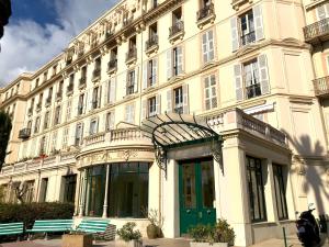 um grande edifício branco com bancos em frente em Résidence du Louvre em Menton