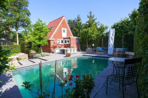 a swimming pool with two chairs and a table in front of a house at Appartement Klein Waldeck in Velp