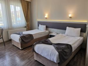 a hotel room with two beds and a chair at Temizay Hotel in Çanakkale
