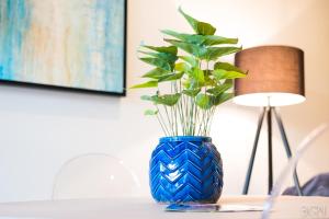 eine blaue Vase mit einer Pflanze auf dem Tisch in der Unterkunft 6 on Bompas Apartments in Johannesburg
