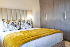 ein Schlafzimmer mit einem Bett mit einer gelben Decke darauf in der Unterkunft 6 on Bompas Apartments in Johannesburg