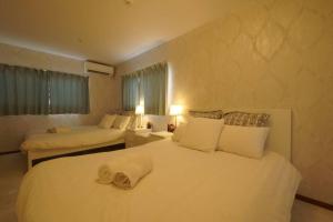 a bedroom with two beds with white sheets and a window at Airstar Hakata House in Fukuoka