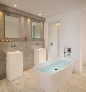 a white bath tub in a bathroom with two mirrors at Mykonos Riviera Hotel & Spa, a member of Small Luxury Hotels of the World in Tourlos