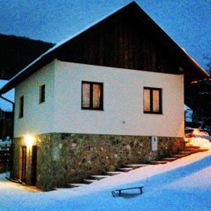 un bâtiment blanc avec un toit noir dans la neige dans l'établissement house s&d, à Otočac