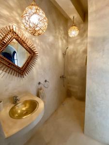 ein Badezimmer mit einem goldenen Waschbecken und einem Spiegel in der Unterkunft Villa Allun Essaouira in Essaouira