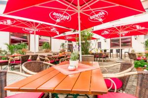 a wooden table with red umbrellas in a restaurant at Hotel- Restaurant Zum Hirsch in Großenlüder