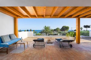 eine Terrasse mit einem blauen Sofa, Tischen und Meerblick in der Unterkunft Romantik Villa in Salema