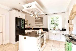 una cucina con mobili bianchi e un frigorifero nero di Georgian Villa in Richmond on the River Swale a Richmond