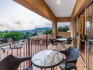 a balcony with tables and chairs and a view at Floracliffe Guesthouse & Events in Roodepoort