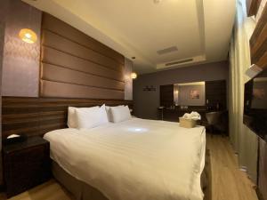 a bedroom with a large white bed with a wooden headboard at IN99 Hotel in Jincheng