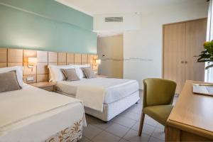 una habitación de hotel con 2 camas y una silla en Ionian Plaza Hotel, en Argostoli