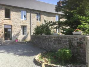 a brick house with a stone wall and a driveway at La Petellerie, maison de campagne avec piscine pour un séjour détente in Moyon