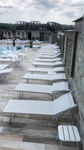 una fila de bancos blancos sentados junto a una piscina en L’INVIDIA, en Novaci-Străini