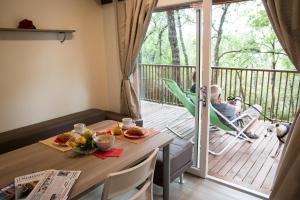 a man is sitting in a chair on a deck with a table at Cerquestra Camping Village in Monte del Lago