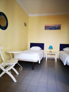a room with two beds and a desk and a table at HI Lagos - Pousada de Juventude in Lagos