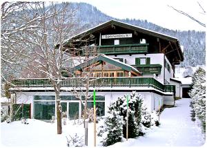 un grande edificio nella neve di fronte di Landhaus Sonnenblick a Reit im Winkl