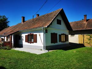 ein kleines weißes Haus mit braunem Dach in der Unterkunft Őrség Kincse Kis Apartman - 4 főre in Hegyhátszentjakab