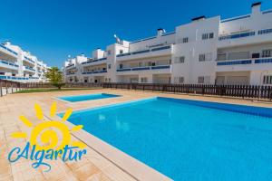 a swimming pool in front of a large building at Santa Luzia Residence Apartamento T2 com Piscina & Wi-Fi in Santa Luzia