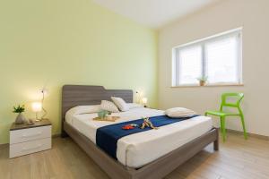 een slaapkamer met een bed en een groene stoel bij Giada 2P - Palazzina Laura MyHo Casa in Tortoreto Lido