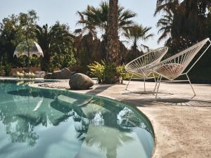 two white chairs sitting next to a swimming pool at Ekies All Senses Resort, a Member of Design Hotels in Vourvourou