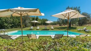 a swimming pool with chairs and umbrellas at FONTE CANNELLA 12&4, Emma Villas in Manciano
