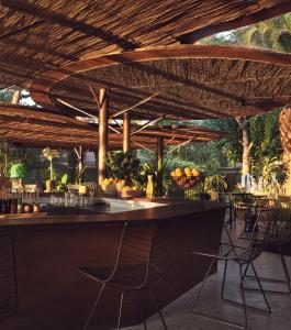 a bar with chairs under a wooden roof at Ekies All Senses Resort in Vourvourou