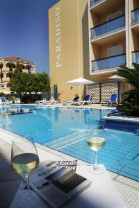 einen Tisch mit zwei Gläsern Wein neben einem Pool in der Unterkunft Hotel Paradiso in Grottammare