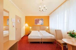 a hotel room with a bed, desk, and a television at Garten- und Kunsthotel Gabriel City in Vienna