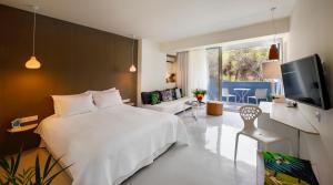 a bedroom with a white bed and a television at Ekies All Senses Resort, a Member of Design Hotels in Vourvourou