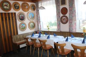 ein Esszimmer mit weißen Tischen, Stühlen und Platten an der Wand in der Unterkunft Gasthaus Zur Waldesruh in Waffenbrunn