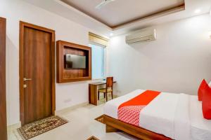 a bedroom with a bed and a television and a door at Hotel Airport View in New Delhi