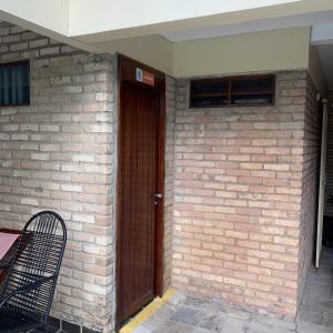 a brick wall with a wooden door and a chair at Manaira Hostel in João Pessoa