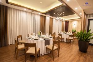 uma sala de jantar com mesas e cadeiras brancas em Purple Lotus Hotel em Hải Dương