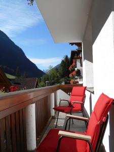 balcón con sillas rojas y vistas a la montaña en Schönes Apartment im Kaunertal en Kaunertal