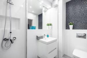 a white bathroom with a shower and a sink at Apartment Antonio in Gdańsk +18 photos