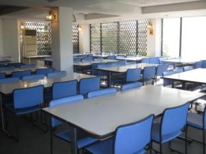 an empty cafeteria with tables and blue chairs at Hotel Madam Mirei in Iiyama