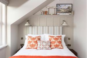 um quarto com uma cama com almofadas laranja e branca em The Whittling House em Alnmouth