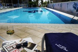 a table with a glass of wine next to a swimming pool at Hotel Paradiso in Grottammare