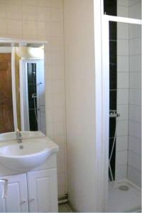La salle de bains blanche est pourvue d'un lavabo et d'une douche. dans l'établissement Maison de 2 chambres avec jardin clos et wifi a Marcillac la Croisille, à Marcillac-la-Croisille