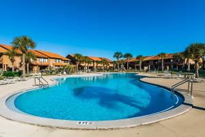 une grande piscine bleue avec des chaises et des palmiers dans l'établissement Gulf Highlands 164 W Leslie Ln, à Panama City Beach