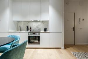 cocina con armarios blancos, mesa y sillas en Hauzify I Apartamento Salamanca en Madrid
