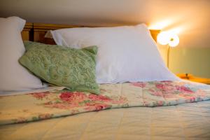 - un lit avec des oreillers blancs et un oreiller vert dans l'établissement Wesley House Holidays - Choice of 2 Quirky Cottages in 4 private acres, à Redruth