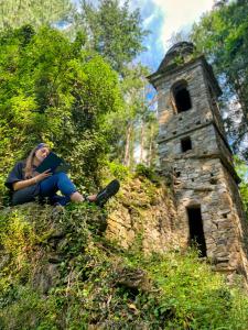Eine Frau, die auf einer Steinmauer mit einem Buch sitzt in der Unterkunft La casa con giardino tra borghi, boschi cascate e natura in Borzonasca