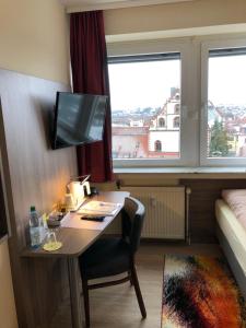 um quarto de hotel com uma secretária e uma cama e um quarto em Hotel Peterchens Mondfahrt em Fulda