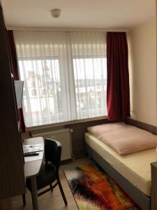 ein kleines Schlafzimmer mit einem Bett, einem Schreibtisch und einem Fenster in der Unterkunft Hotel Peterchens Mondfahrt in Fulda