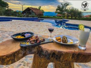 una mesa con platos de comida y una copa de vino en La Victoria Hotel Campestre, en Quimbaya